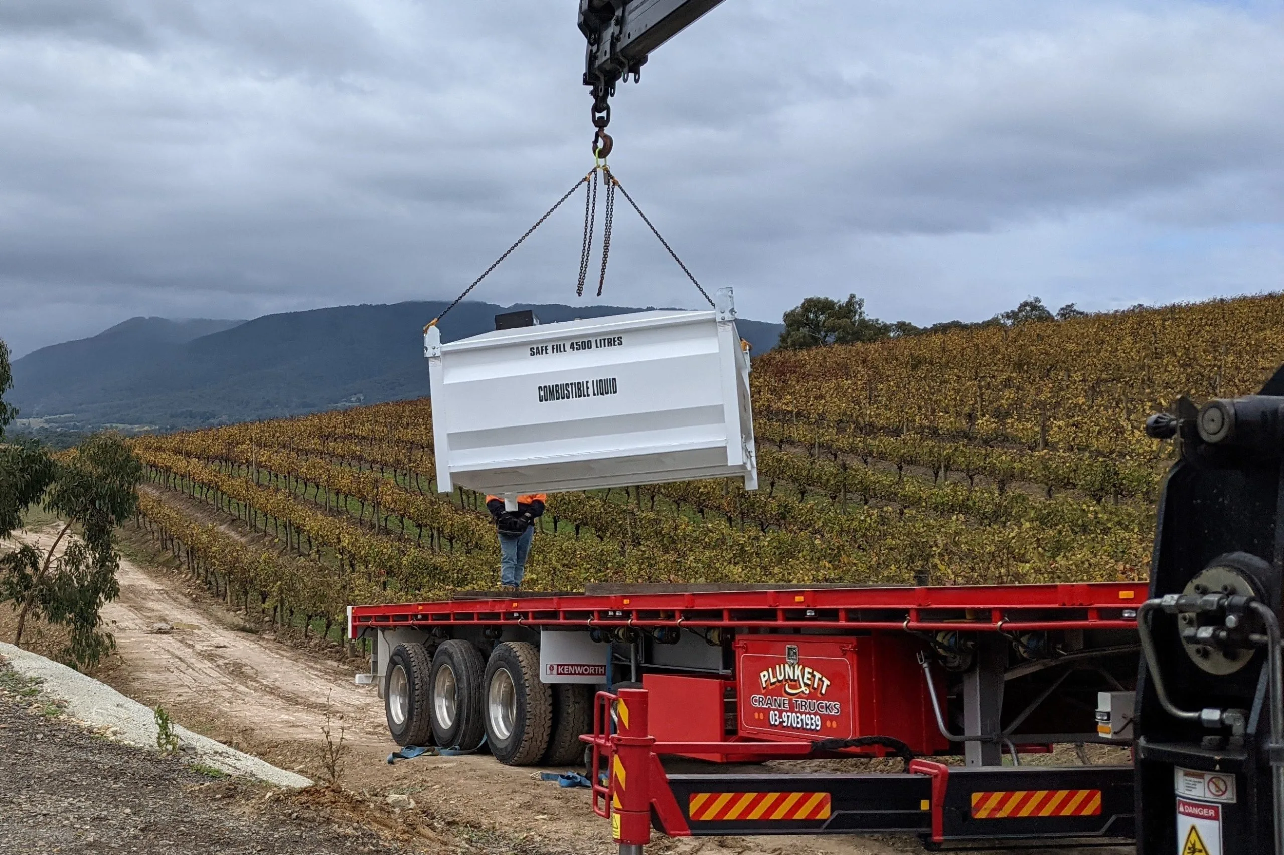 A crane lifting a bulk fuel tank into place at a rural site