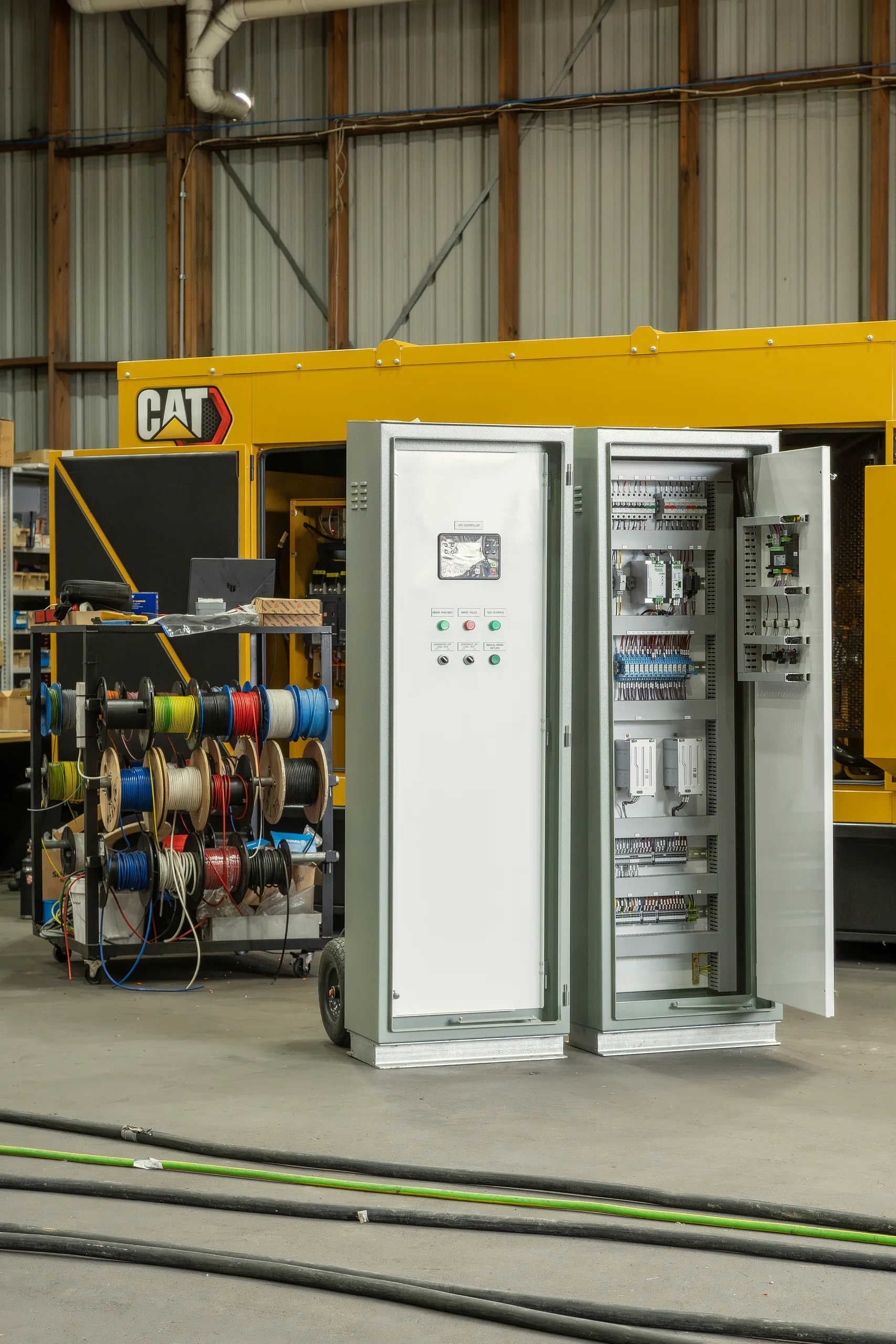 Control cabinets beside a CAT generator in a warehouse