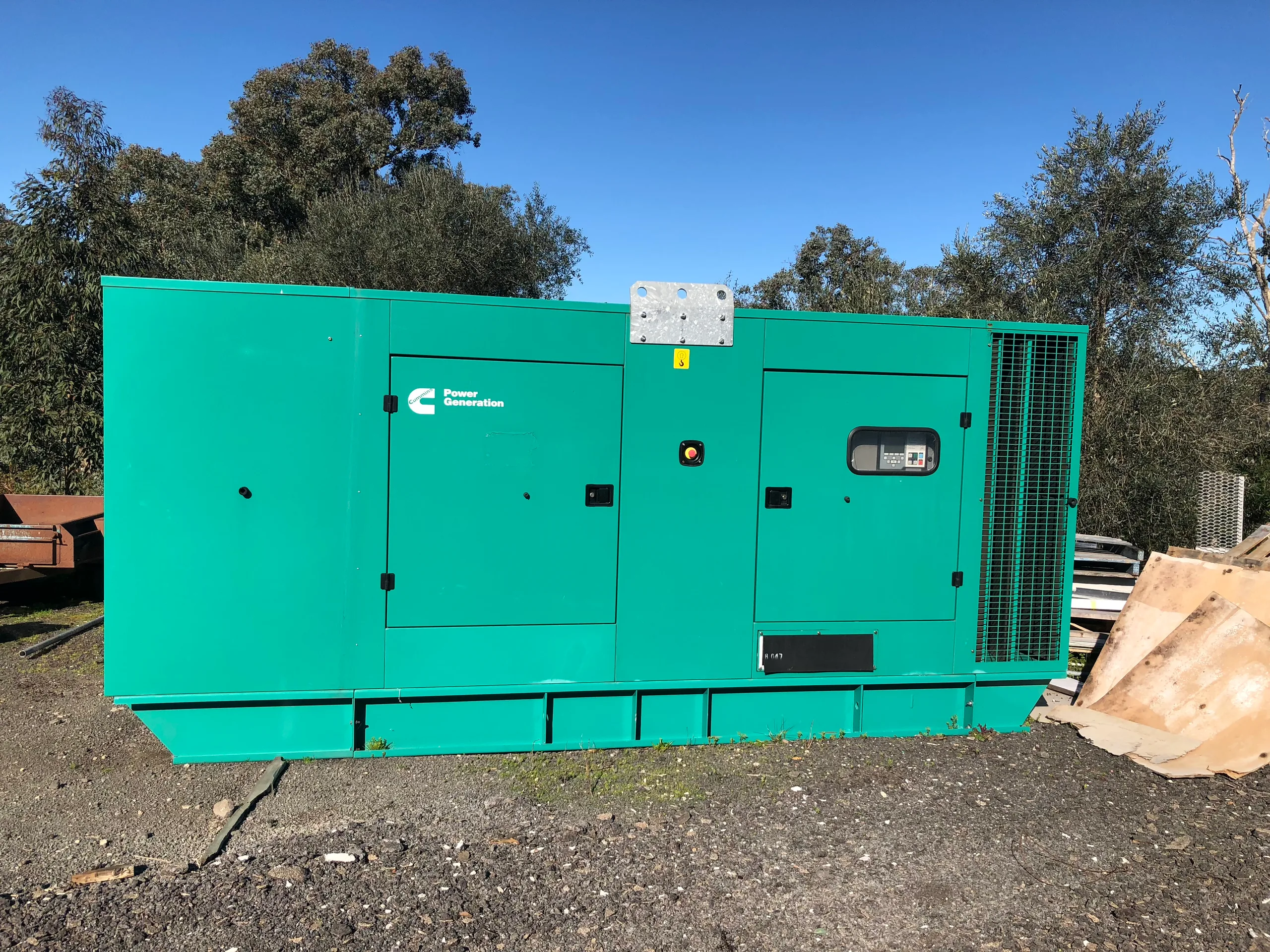 A canopied generator set up outdoors among gum trees