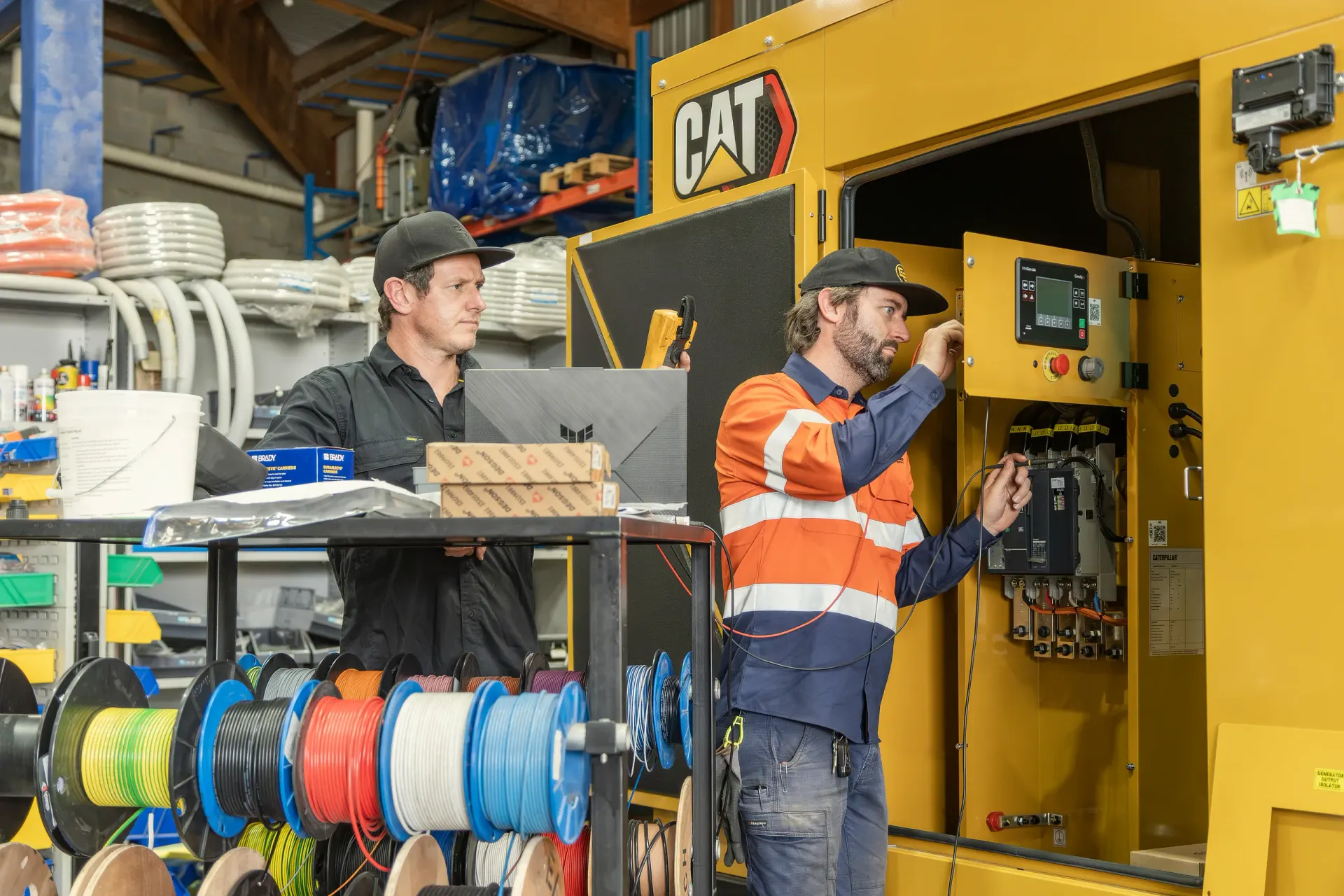 Two Eastern Generators technicians at a Caterpillar control panel