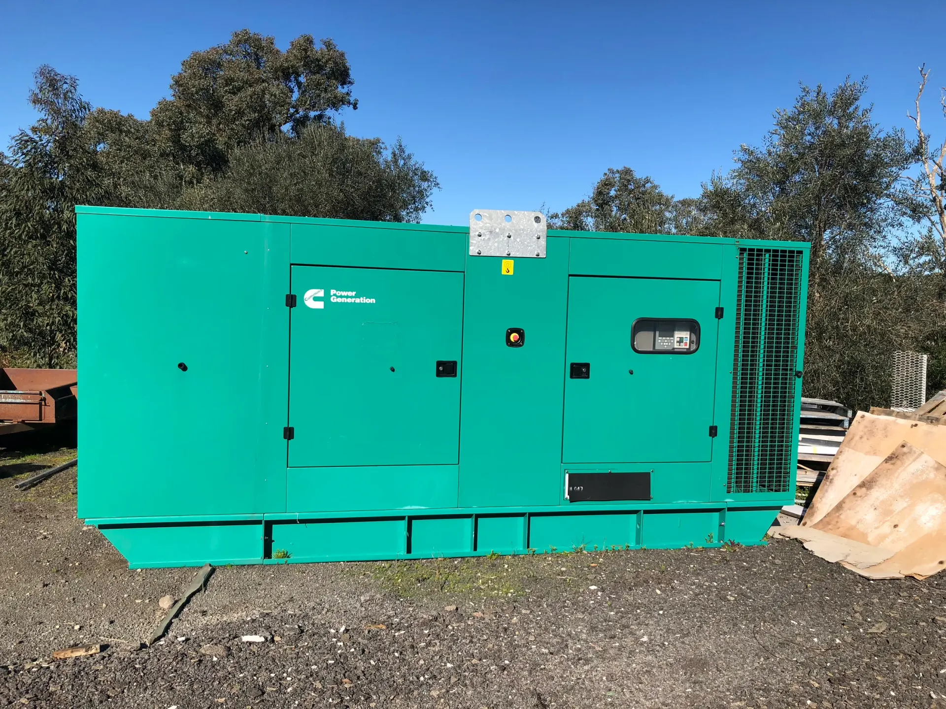 A canopied generator set up outdoors among gum trees