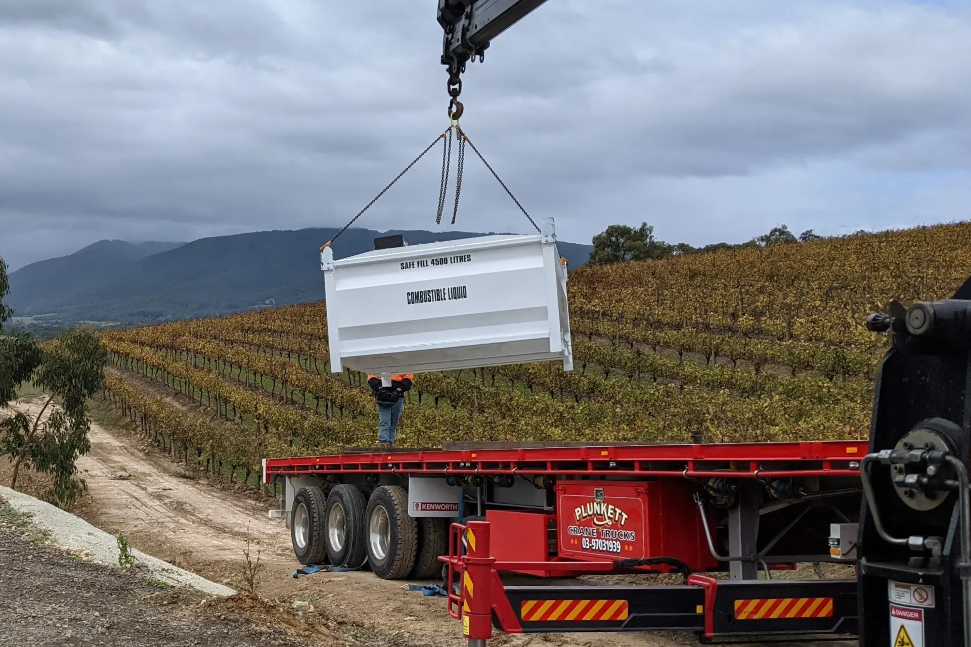 A bulk fuel tank being craned onto a trailer for an Eastern Generators site installation